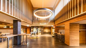 A spacious lobby with wooden paneling, a central sculpture, and a circular light fixture. - FAIR RESORT All Inclusive Wellness & SPA Hotel Jena (Zollnitz)
