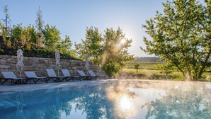 A clear swimming pool with lounge chairs and umbrellas, surrounded by stone walls and trees. - FAIR RESORT All Inclusive Wellness & SPA Hotel Jena (Zollnitz)