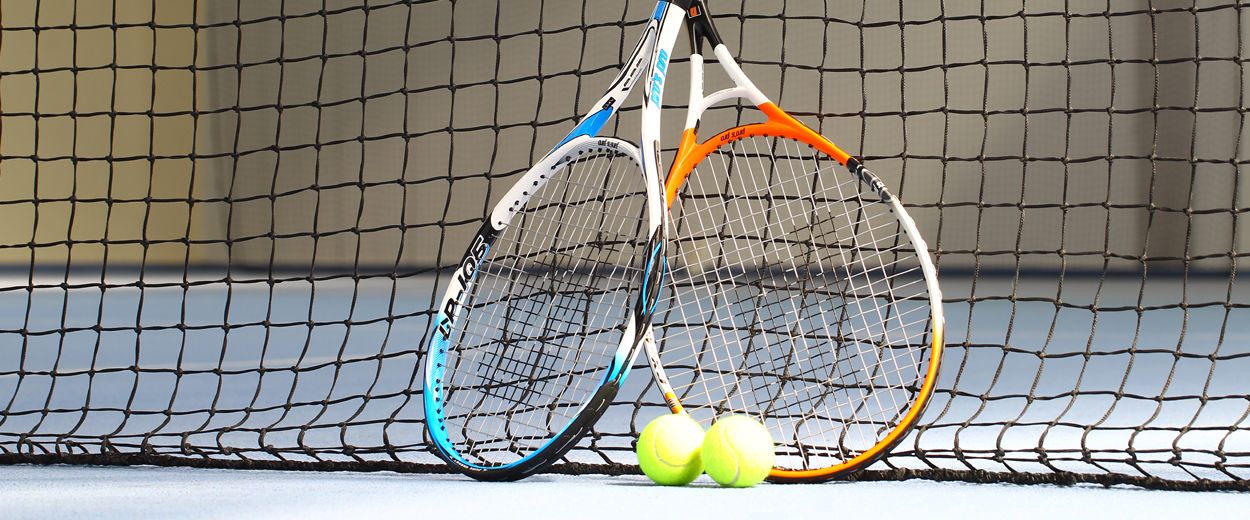 Two tennis rackets and three tennis balls on a net.