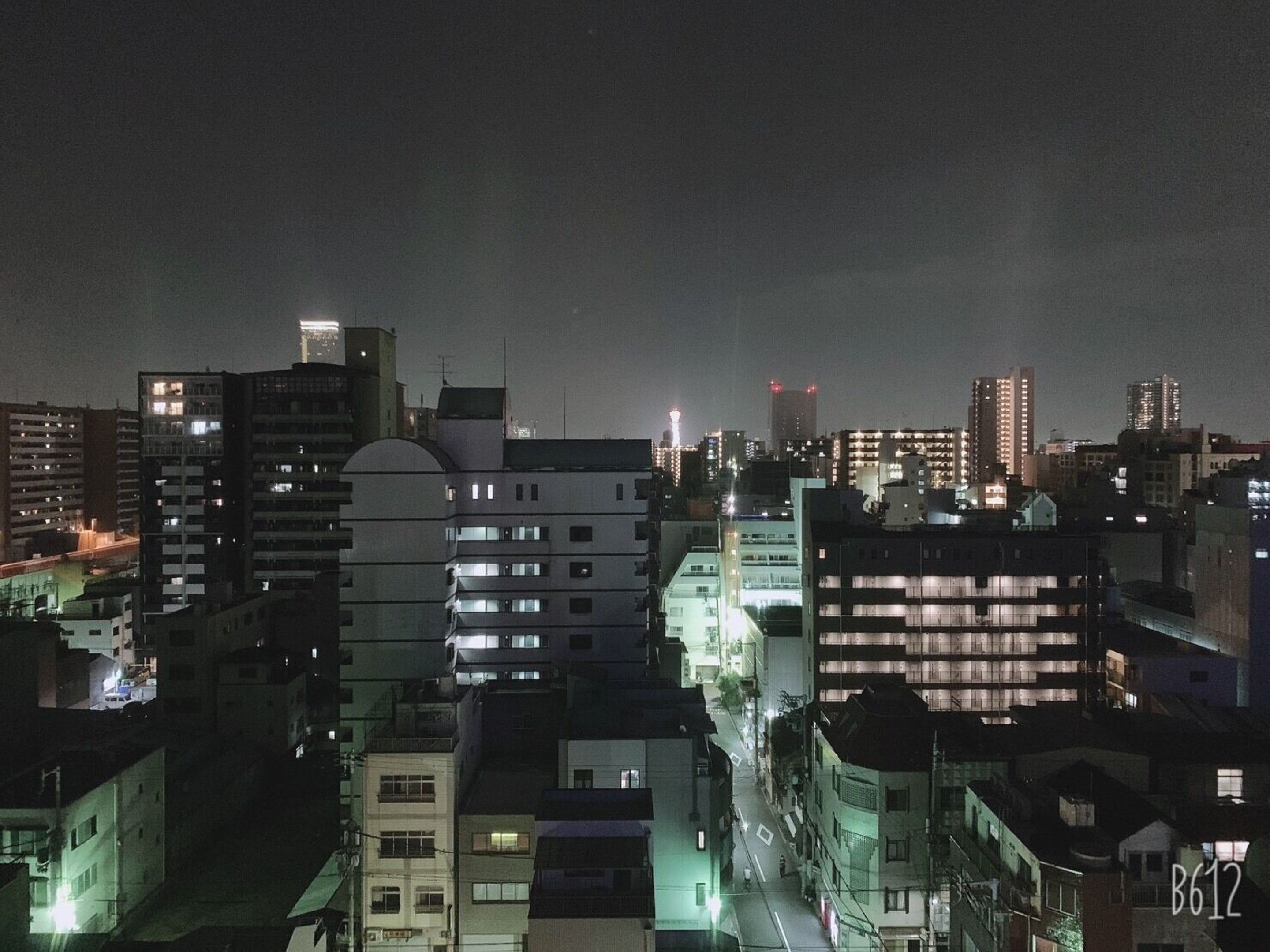 A nighttime cityscape with various buildings, including a prominent tower with lights.