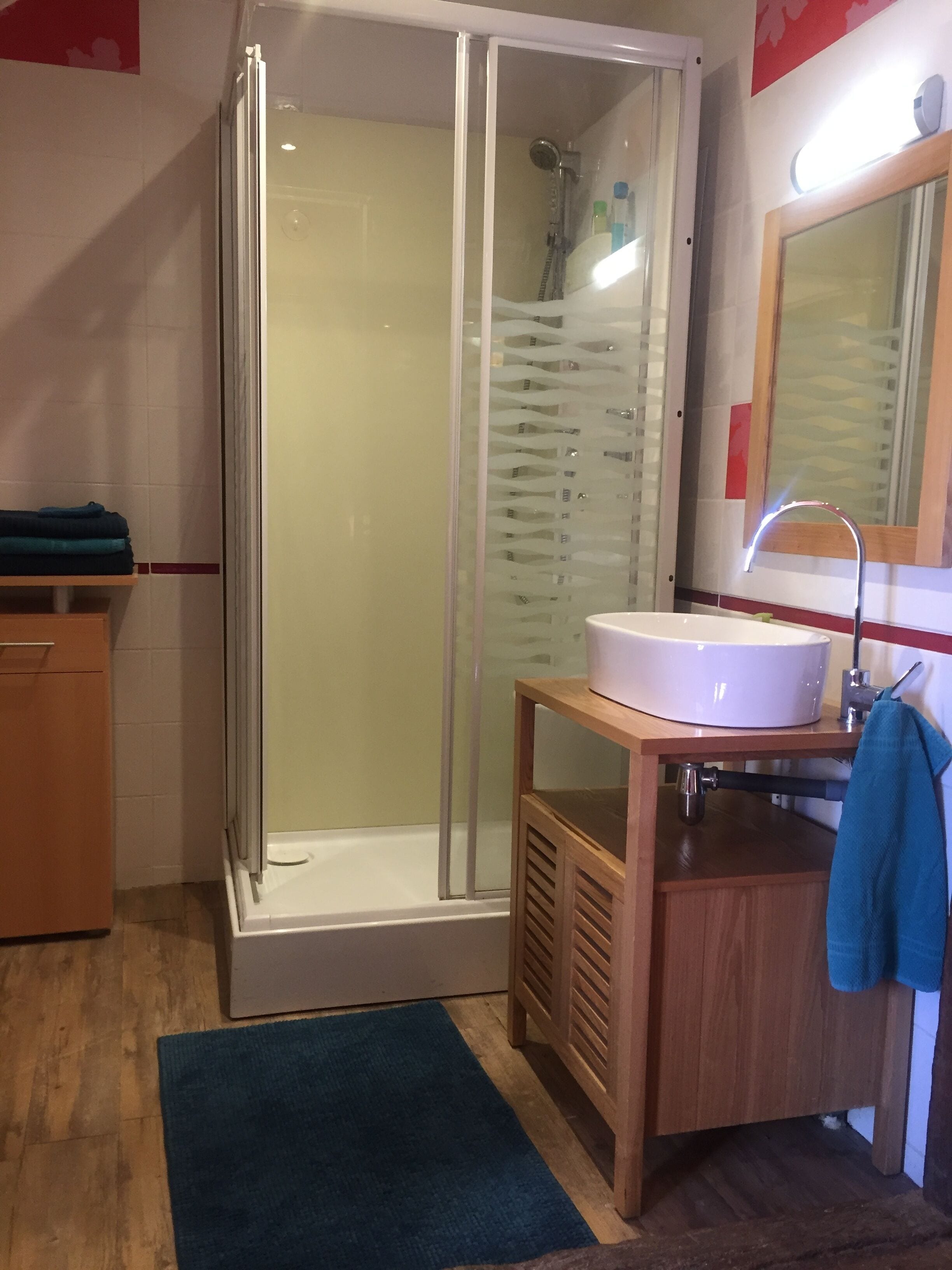 A modern bathroom with a glass-enclosed shower, a white sink, and a wooden vanity.