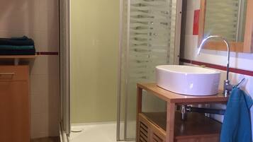 A modern bathroom with a glass-enclosed shower, a white sink, and a wooden vanity.