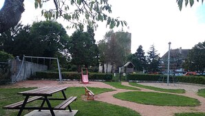 Un parque con una mesa de picnic, equipo para juegos infantiles y un sendero sinuoso.
