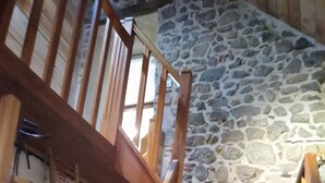 Una escalera de madera con estanterías a cada lado, que conduce a un muro de piedra.