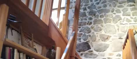 A wooden staircase with bookshelves on either side, leading to a stone wall.