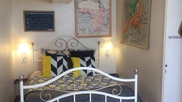 A bedroom with a bed, two wall-mounted lamps, a map, and a framed picture.