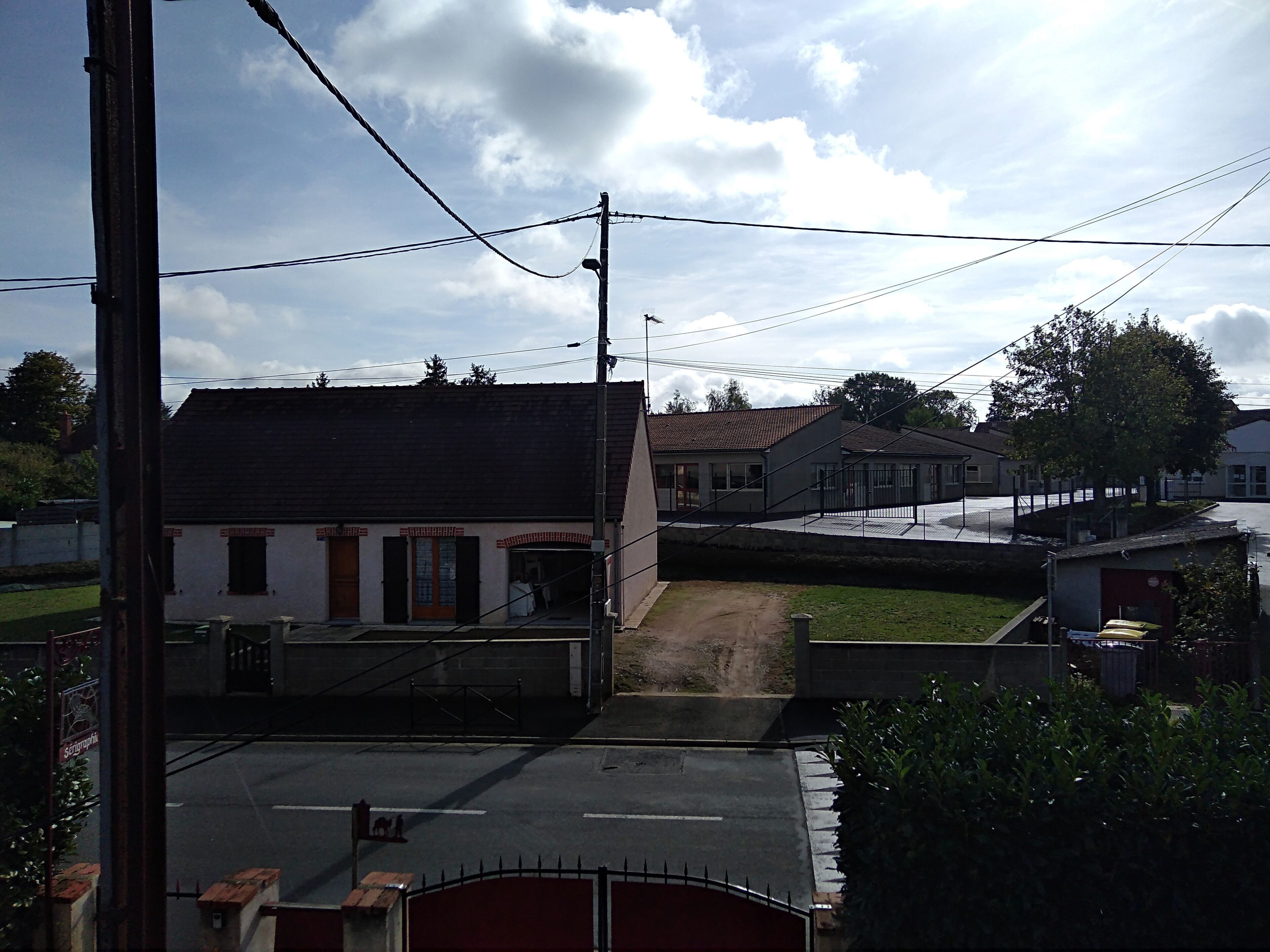 Un bâtiment avec un toit rouge, une petite entrée et une zone pavée devant.
