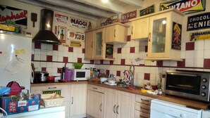 Una cocina con armarios de madera, un microondas, horno tostador y varios utensilios de cocina sobre la encimera.