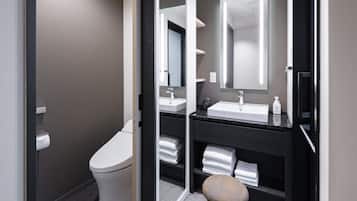 A modern bathroom with a toilet, a sink, a mirror, and a towel rack.
