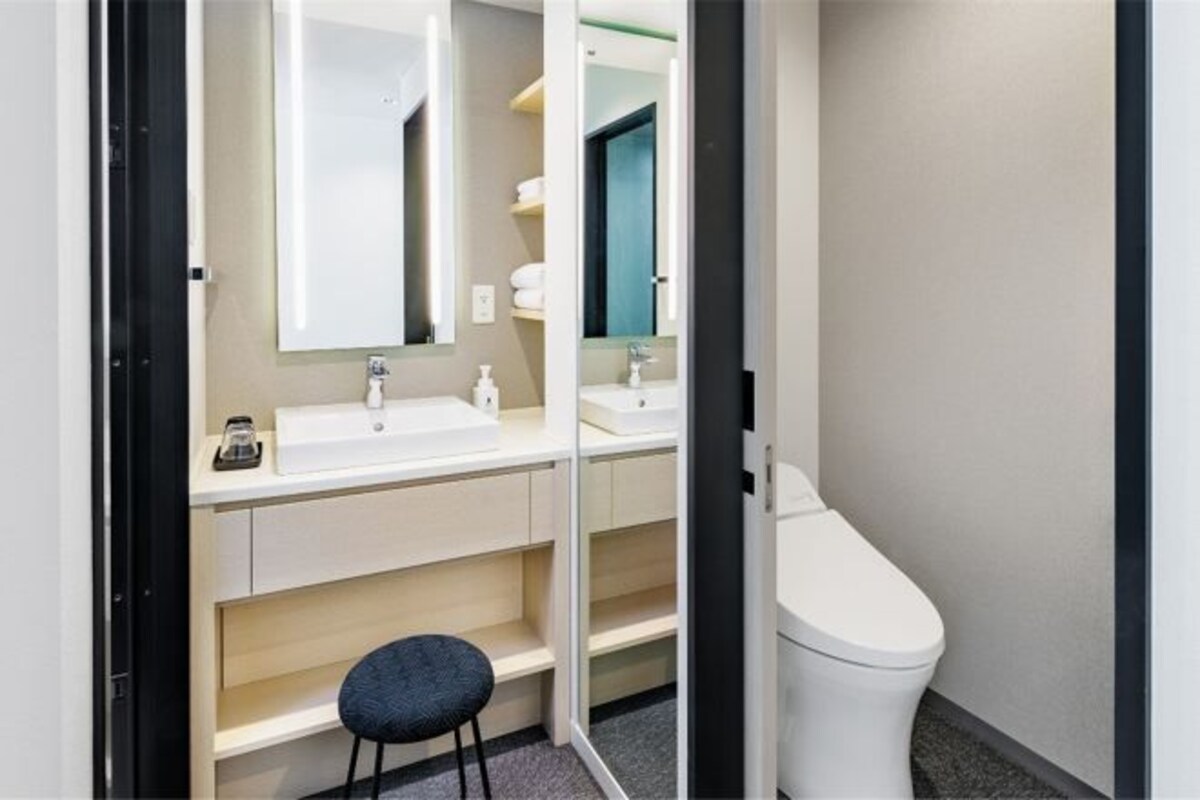 A modern bathroom with a white sink, mirror, and toilet.