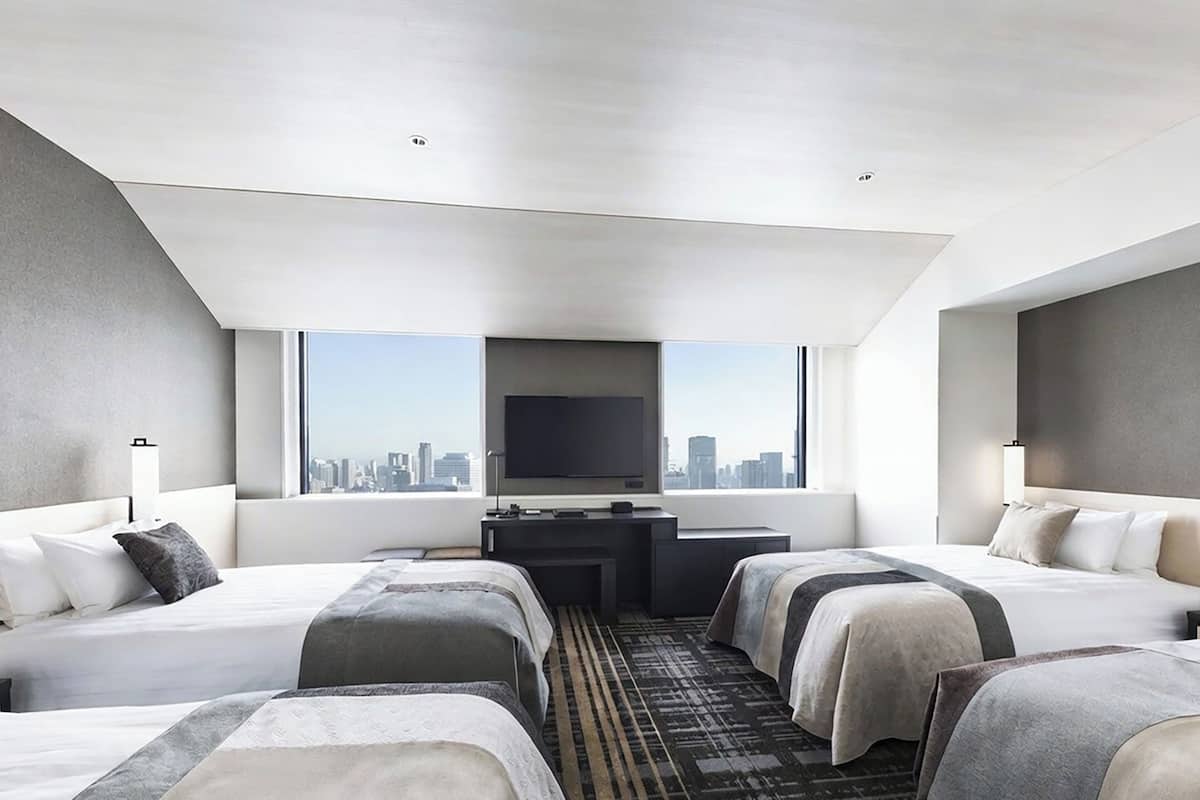 Ein modernes Hotelzimmer mit zwei Betten, einem Schreibtisch und einem großen Fernseher.