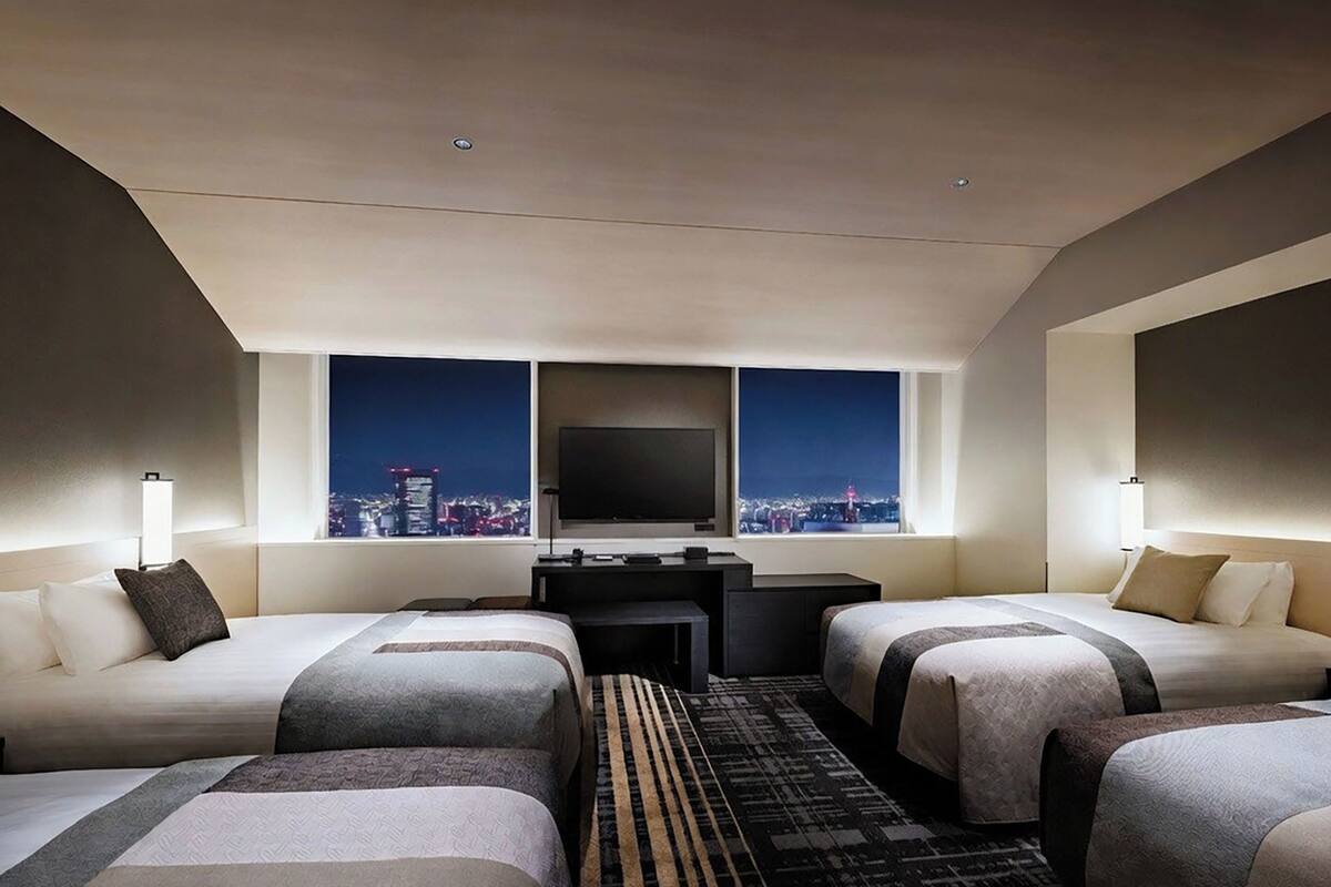 Ein Hotelzimmer mit zwei Betten, einem Fernseher und Blick auf die Stadt.