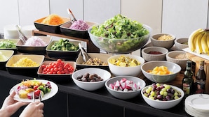 A buffet table with various food items and a person serving themselves.