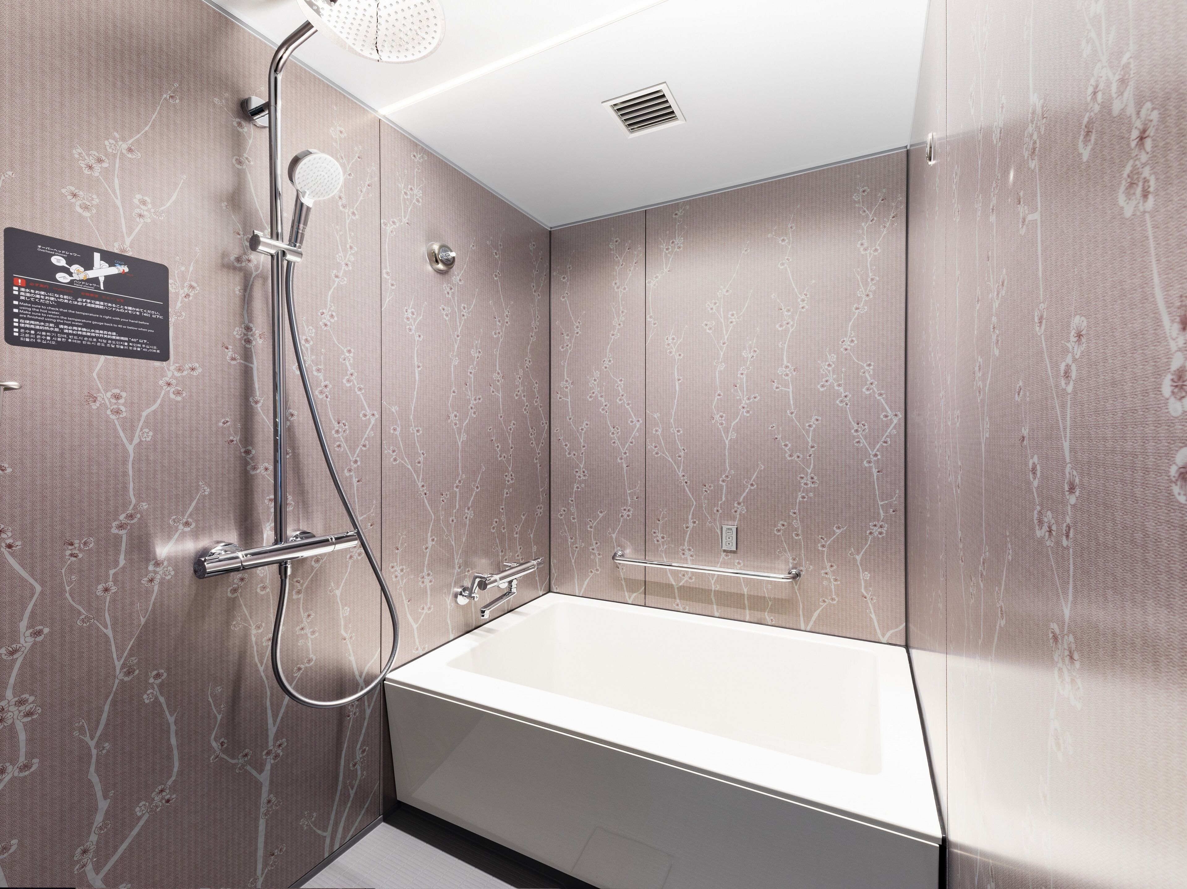 Een moderne badkamer met een vrijstaand bad, een handdouche en een wandmengkraan.