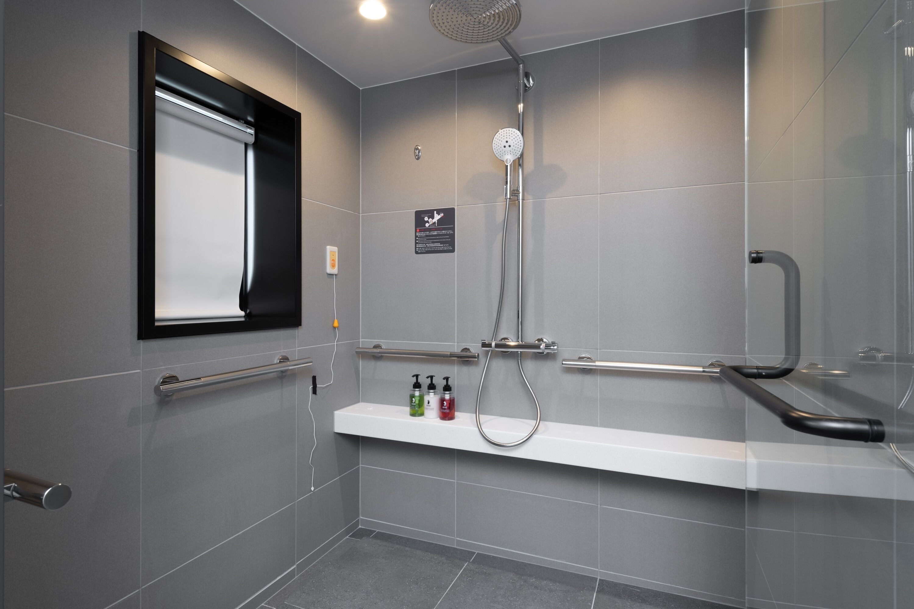 Une douche moderne dotée d’un pommeau de douche à main, d’un espace de douche clos par des parois de verre et d’une étagère pour les articles de toilette.