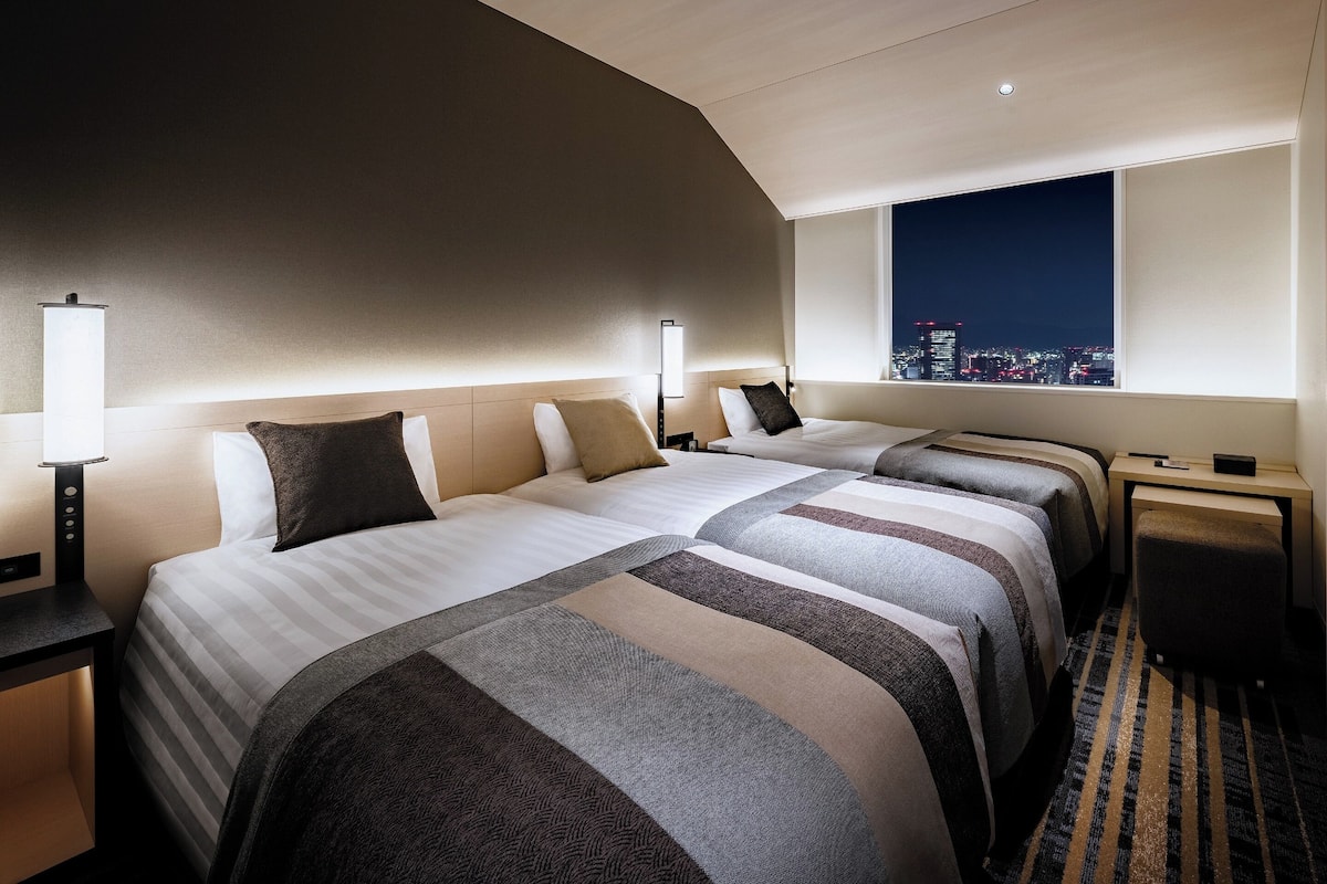 Ein Hotelzimmer mit zwei Betten, Blick auf die Stadt und modernem Design.