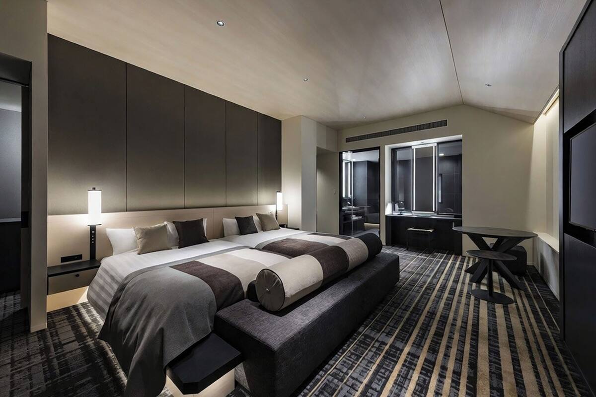 Ein modernes Hotelzimmer mit einem großen Bett, einer Sitzecke, einem Schreibtisch und einem Spiegel.
