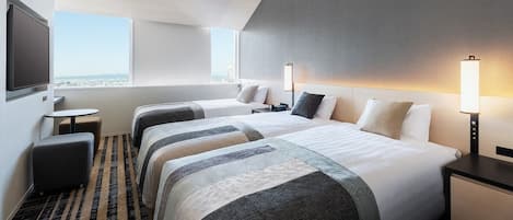 A hotel room with two beds, a desk, a chair, and a large window with a city view.