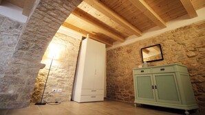 Une pièce aux murs de pierre, avec des poutres en bois, une armoire blanche et un meuble vert.