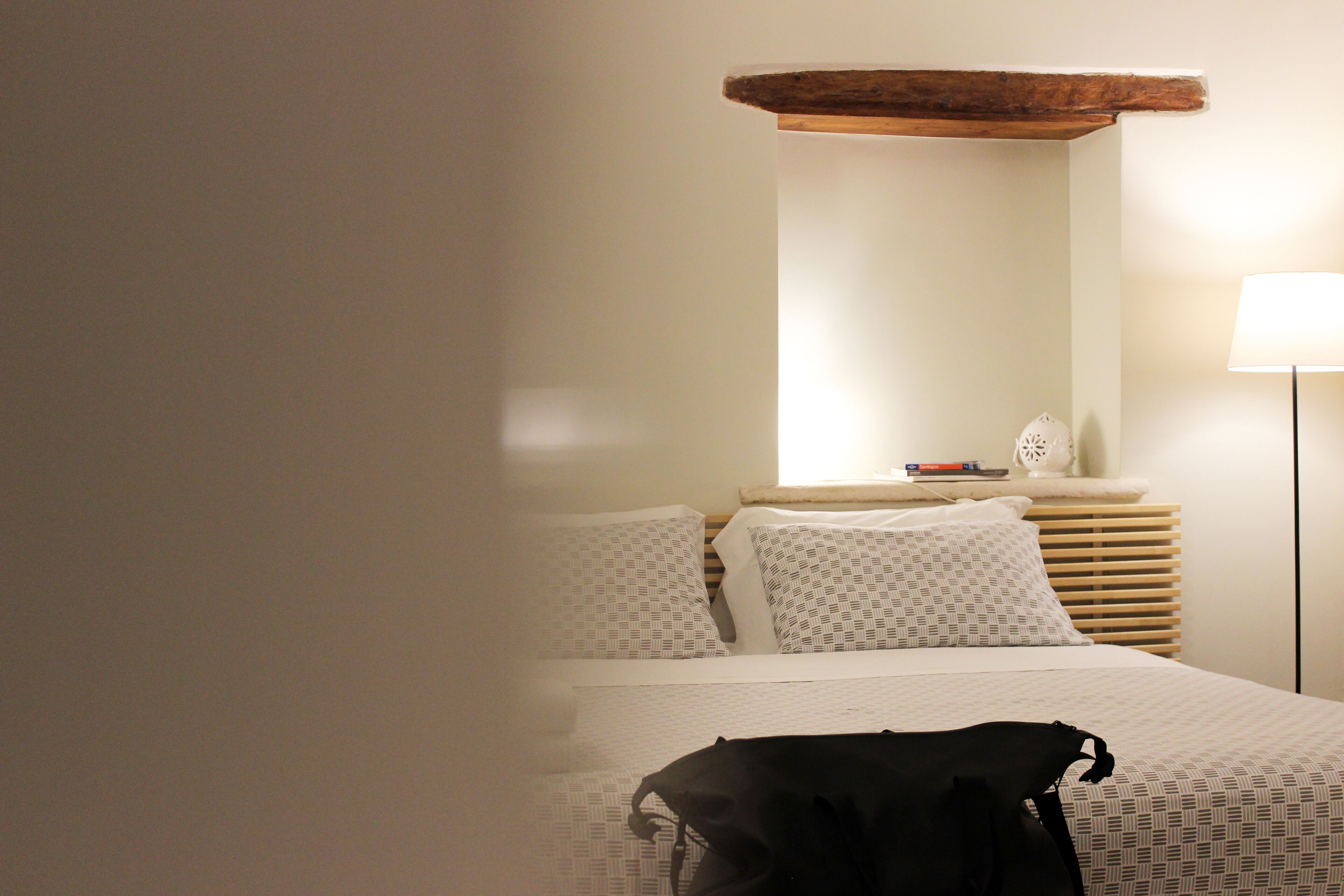 A hotel room with a bed, a bedside lamp, and a wooden headboard.