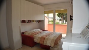 A bedroom with a bed, built-in wardrobe, and a view of the outside. - GuestHost - Our studio is located 5 minutes walk from the beach, in the most beautiful area of Sanremo. With a small terrace with sea view and free unassigned condominium parking, (subject to availability) the apartment is waiting for you in the city of  (Sanremo)