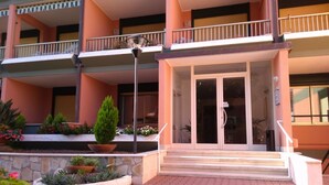 A multi-story hotel with a central entrance, balconies, and a landscaped garden area. - GuestHost - Our studio is located 5 minutes walk from the beach, in the most beautiful area of Sanremo. With a small terrace with sea view and free unassigned condominium parking, (subject to availability) the apartment is waiting for you in the city of  (Sanremo)