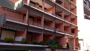 A multi-story hotel with balconies, a stone facade, and outdoor plants. - GuestHost - Our studio is located 5 minutes walk from the beach, in the most beautiful area of Sanremo. With a small terrace with sea view and free unassigned condominium parking, (subject to availability) the apartment is waiting for you in the city of  (Sanremo)