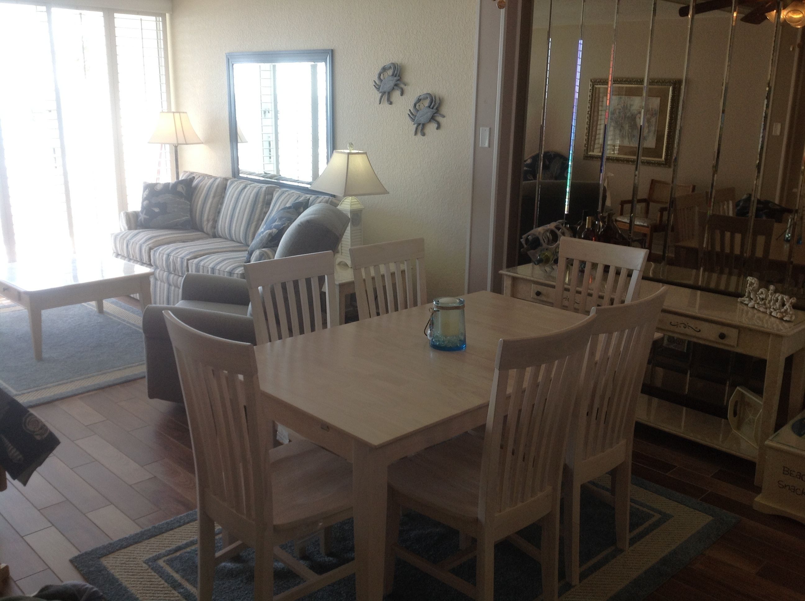 A dining area with a table and chairs, a sofa, a lamp, and a window with blinds.