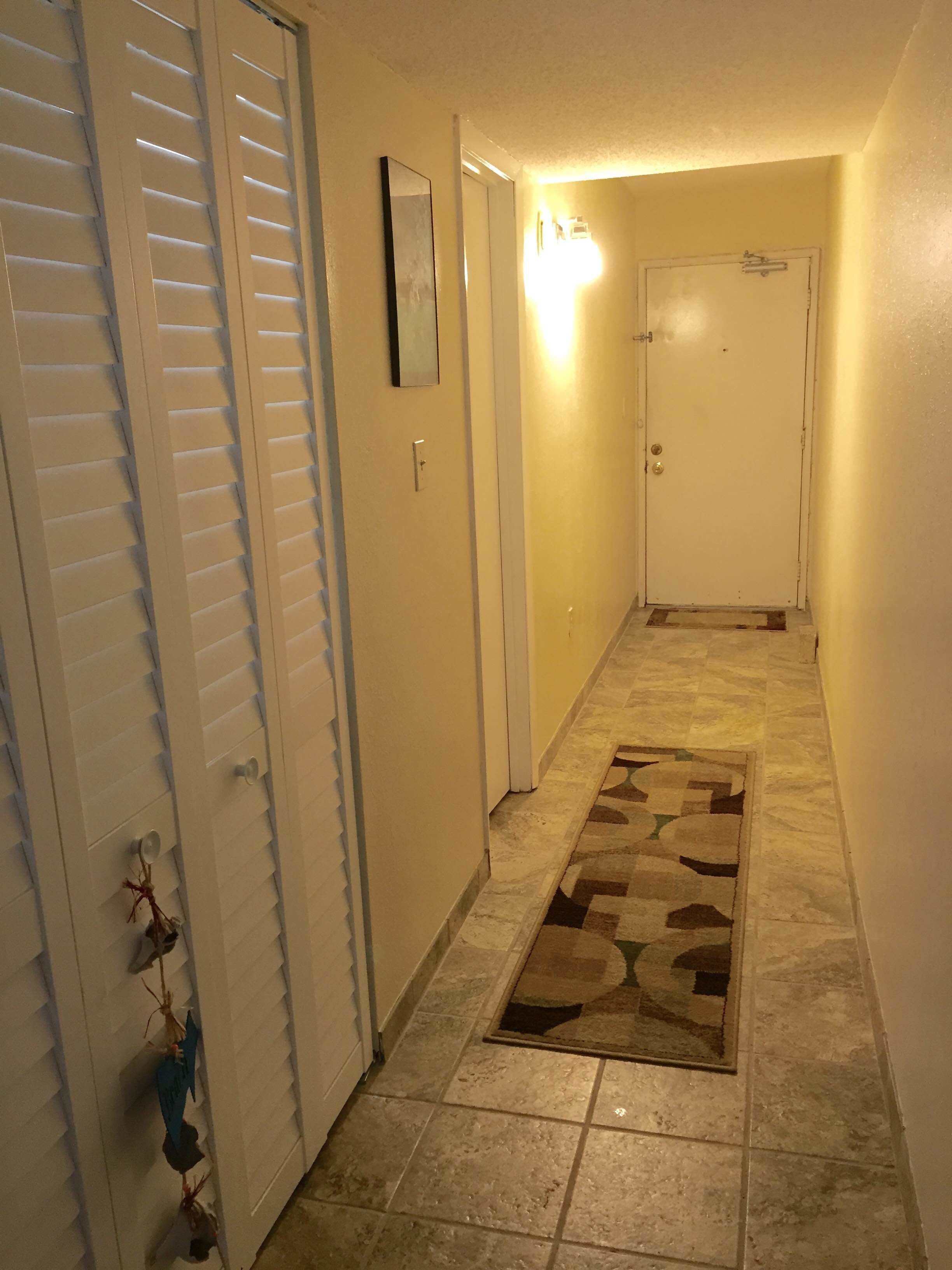 A hallway with a patterned rug, white doors, and a light switch on the wall.
