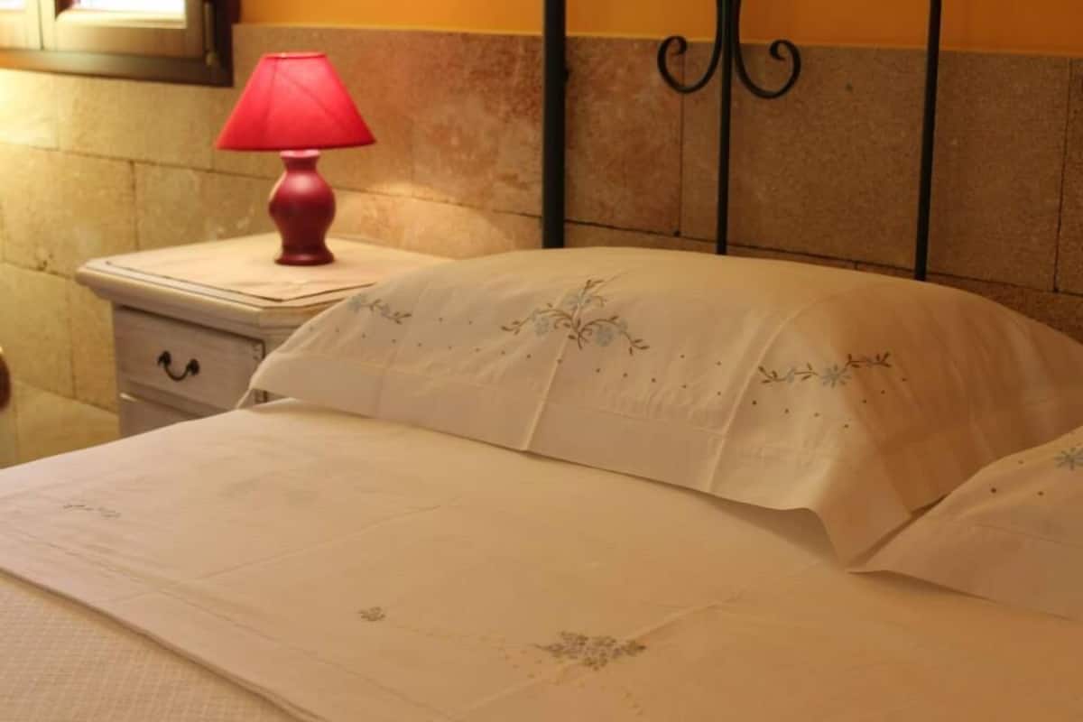 A neatly made bed with a white bedspread and a red lamp on a bedside table.