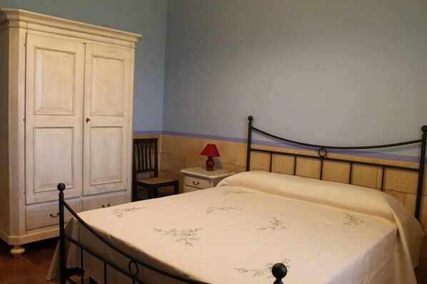 A bedroom with a bed, a nightstand, a red lamp, and a white wardrobe. - B&B Elda Salento (Tuglie)