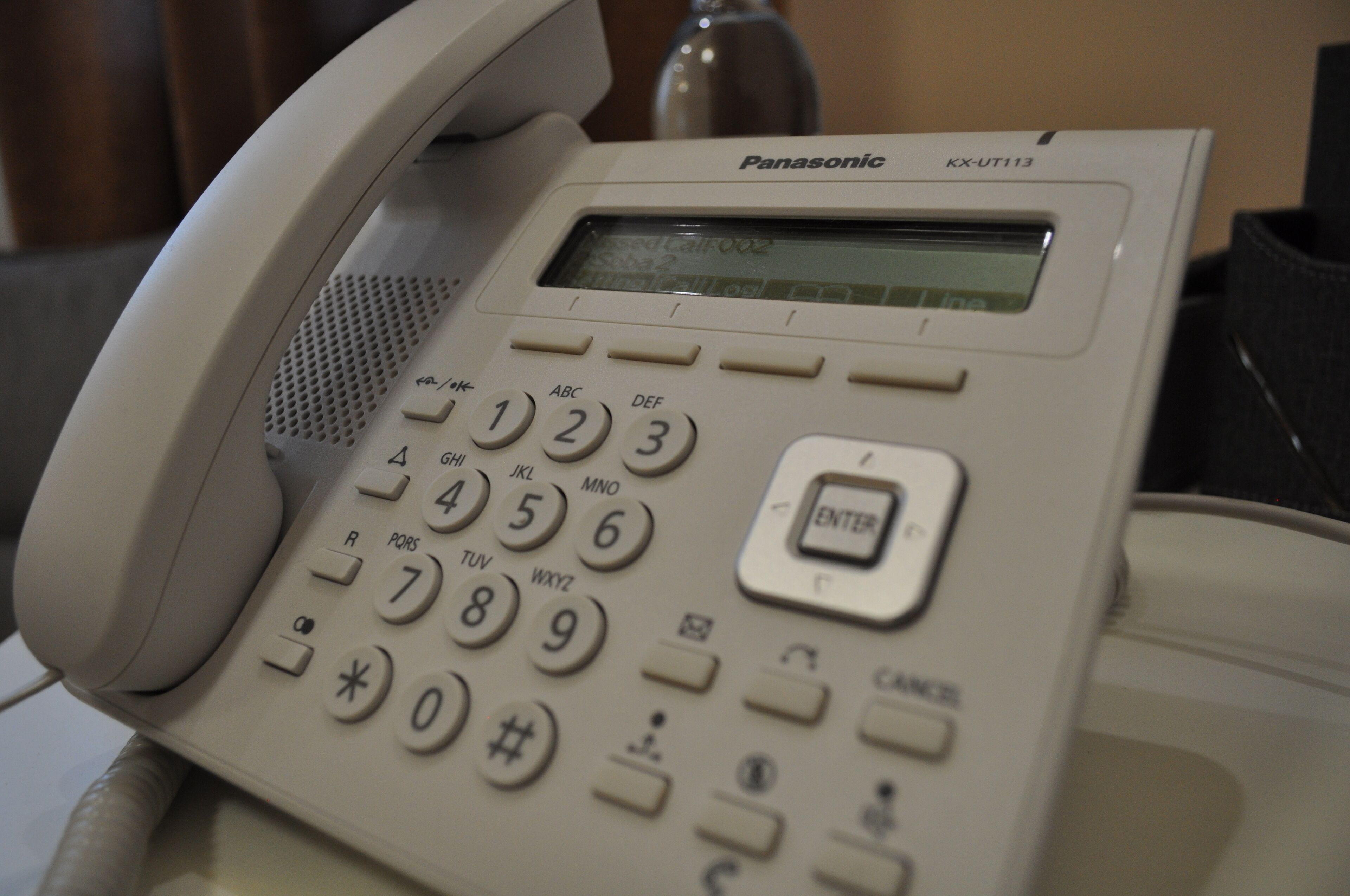 Un teléfono de oficina Panasonic KX-UT113 con teclado numérico y una pequeña pantalla.
