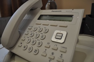 Un teléfono de oficina Panasonic KX-UT113 con teclado numérico y una pequeña pantalla.