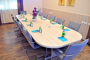 Ett konferensrum med ett långt bord, stolar och en vas med blommor.