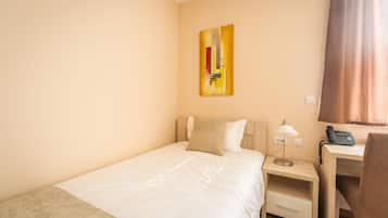 Ein Hotelzimmer mit Bett, Schreibtisch, Lampe, Telefon und einem Gemälde an der Wand.