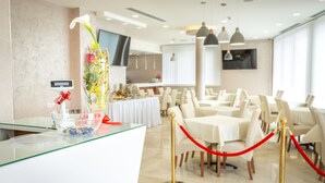 A hotel reception area with a glass counter, a vase with flowers, and a red rope barrier. - Hotel Mar Garni (Belgrade)