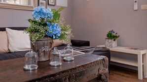 Een rustieke houten tafel met een vaas blauwe bloemen en drie glazen stolpkaarsen.