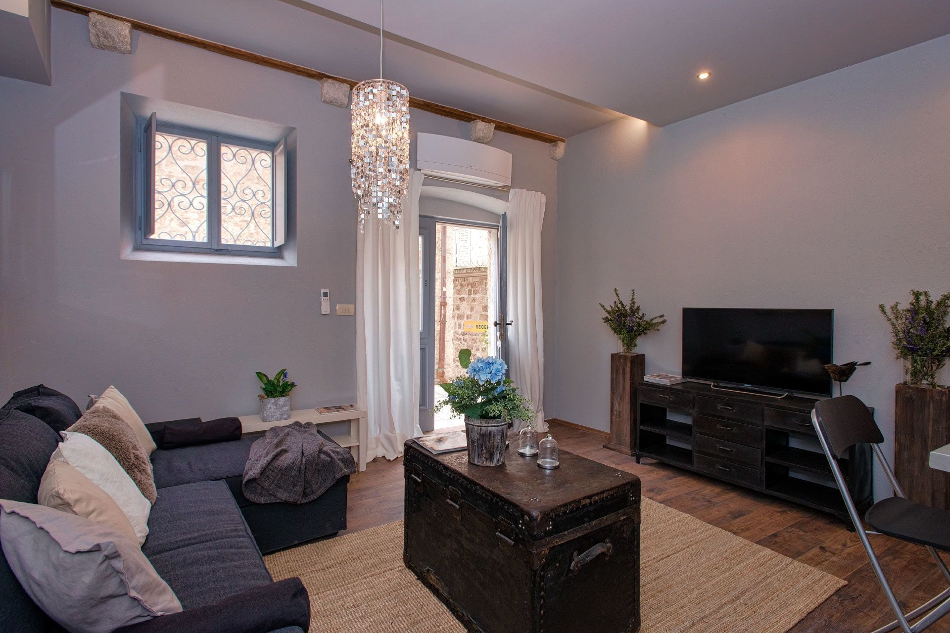 A living room with a sofa, a coffee table, a TV, and decorative plants.