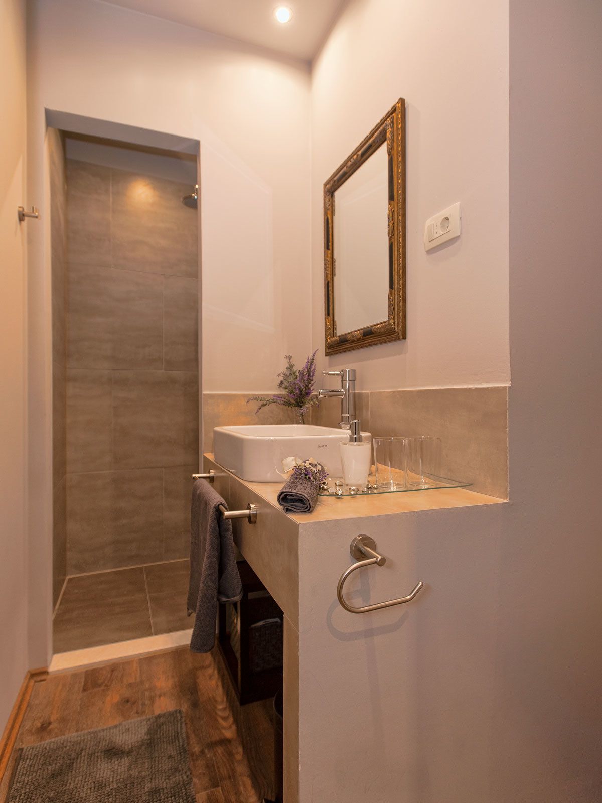 A modern bathroom with a shower, a sink with a mirror, and a towel rack.