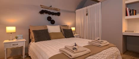 Un dormitorio con una cama grande, dos mesitas de noche, una estantería y un adorno en la pared.