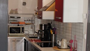 Kompakti keittiö, jossa on mikroaaltouuni, kahvinkeitin ja ruostumattomasta teräksestä valmistetut kodinkoneet.