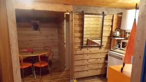 A wooden interior with a dining area, a kitchen, and a bathroom. - Yourte Mongole (Huriel)