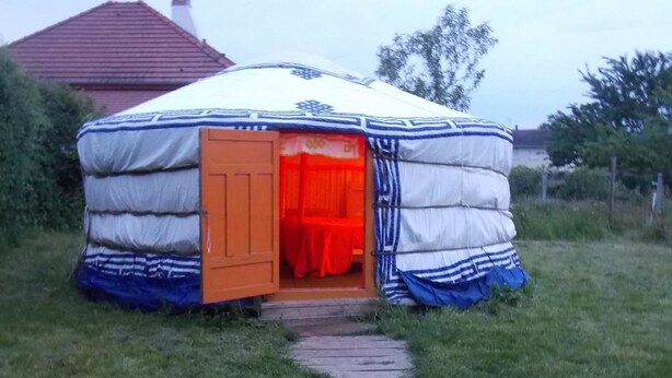 A yurt with an open door revealing a red interior. - Yourte Mongole (Huriel)