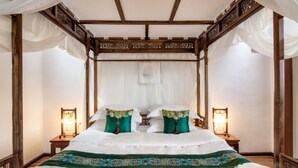 A four-poster bed with white linens and green pillows, wooden headboard, and two bedside tables with lamps. - Meili Xiangyue Villa Verde (Dali)