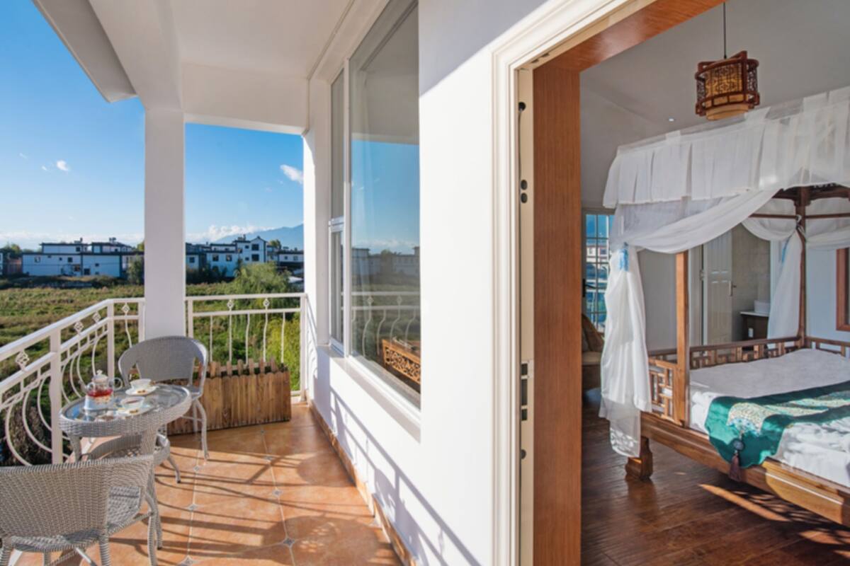 Ein Balkon mit Korbmöbeln und Blick auf Gebäude in der Ferne.
