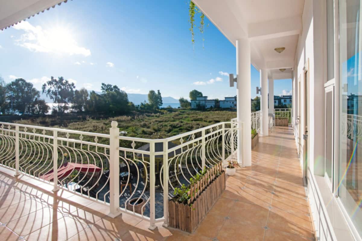 Ein Balkon mit weißer Geländer, Blick auf die Landschaft und klarer Himmel.