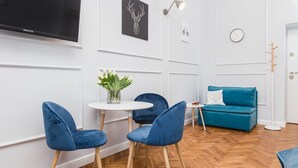 A modern living room with a white wall, a blue sofa, and a round table with chairs. - The Old Town View (Kraków)