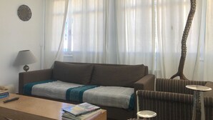 A living room with a sofa, a coffee table with books, a lamp, and a giraffe statue. - Cosy Marsa Plage (La Marsa)