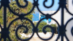 A view through ornate metalwork, featuring a building with a blue facade and a white wall. - Cosy Marsa Plage (La Marsa)