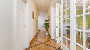 A hallway with wooden flooring, white doors, and a potted plant. - Apartamenty w Pałacu Pod Baranami (Kraków)